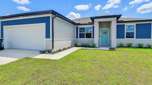 A residential house with a garage, a front door, and a small front yard. - Home < 1-mi Walk to Warm Mineral Springs Park! (North Port)