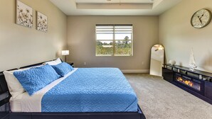 Ein Schlafzimmer mit Bett, Deckenventilator, Kamin, einer Uhr und einem Fenster mit Jalousien.
