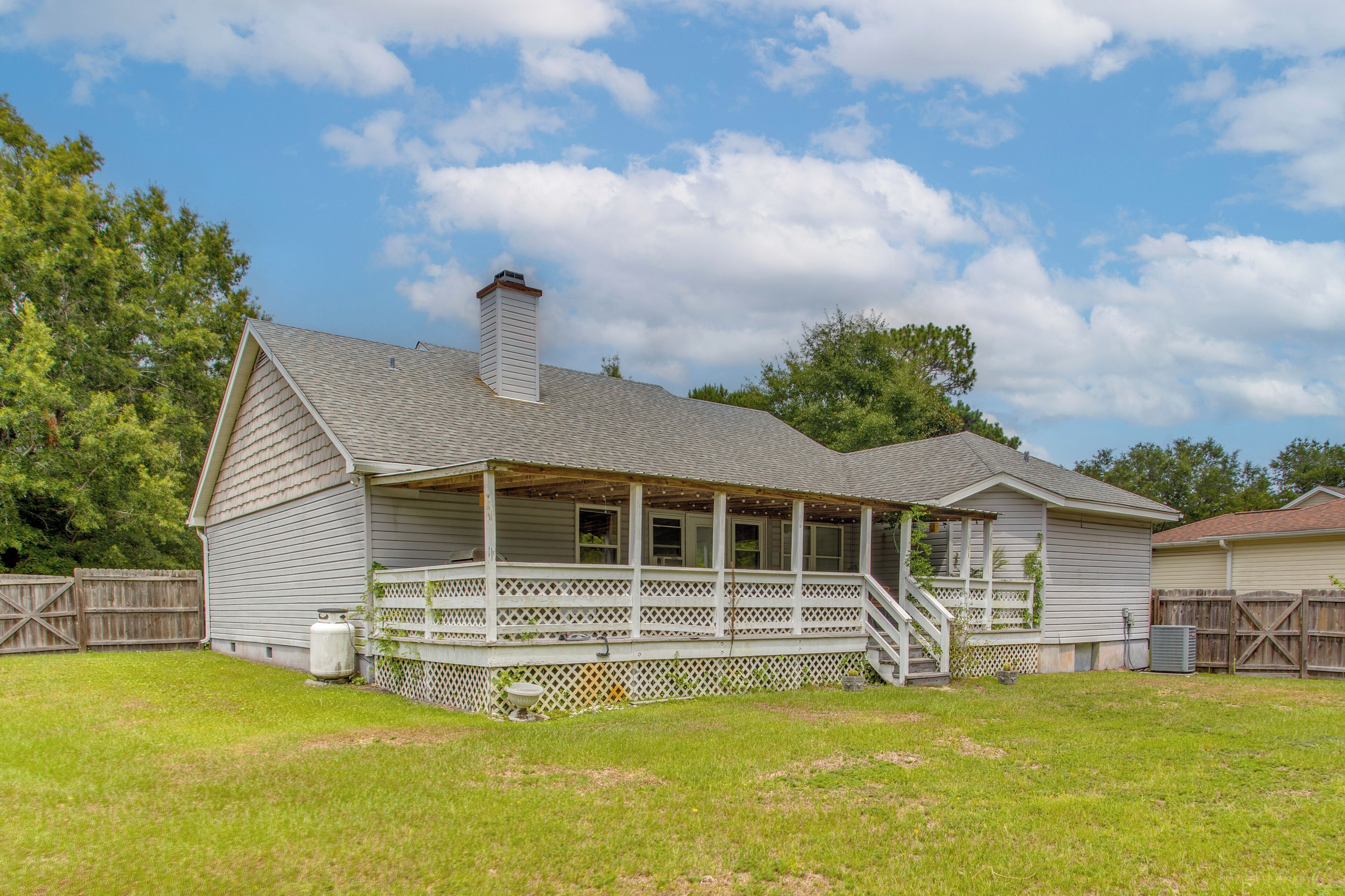 A single-story house with a porch, a chimney, and a fenced yard.