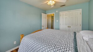 Un dormitorio con cama, ventilador de techo y dos puertas blancas.
