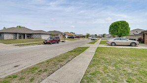 Una calle residencial con casas, aceras y coches aparcados.