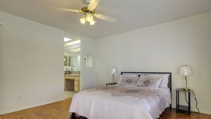 Um quarto com uma cama, um ventilador de teto, uma mesa de cabeceira e uma luminária.