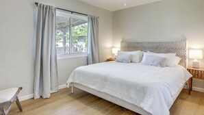 Ein Schlafzimmer mit Bett, Deckenventilator, Fenster mit Vorhängen und Nachttisch mit Lampe.