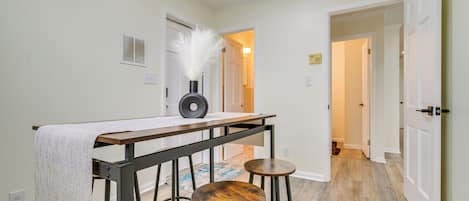 A hallway with a table and stools, a door, and a patterned rug.