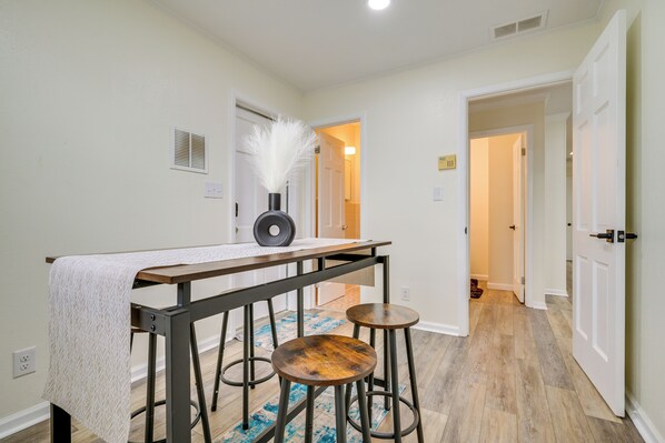 A hallway with a table and stools, a door, and a patterned rug.