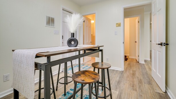 Un couloir avec une table et des tabourets, une porte et un tapis à motifs.