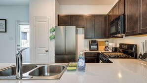 Una cucina moderna con elettrodomestici in acciaio inossidabile, un lavello doppio e mobili in legno.