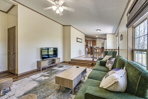 A living room with a green sofa, a wooden coffee table, and a television. - History & Nature Hub! Family Gem in Fayetteville (Fayetteville)