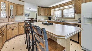 Une cuisine avec des meubles en bois, un îlot central et des tabourets de bar.