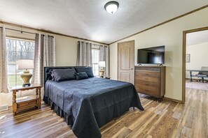 A bedroom with a bed, dresser, TV, and a window with curtains. - History & Nature Hub! Family Gem in Fayetteville (Fayetteville)