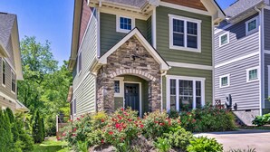 A two-story house with a stone facade, green siding, and a well-maintained garden with red flowers. - Modern Black Mountain Cottage: 17 Mi to Asheville! (Black Mountain)