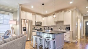 A modern kitchen with white cabinetry, stainless steel appliances, a central island with bar stools, and pendant lighting. - Modern Black Mountain Cottage: 17 Mi to Asheville! (Black Mountain)