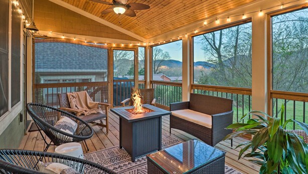 A covered outdoor deck with wicker furniture, a fire pit, and string lights. - Modern Black Mountain Cottage: 17 Mi to Asheville! (Black Mountain)