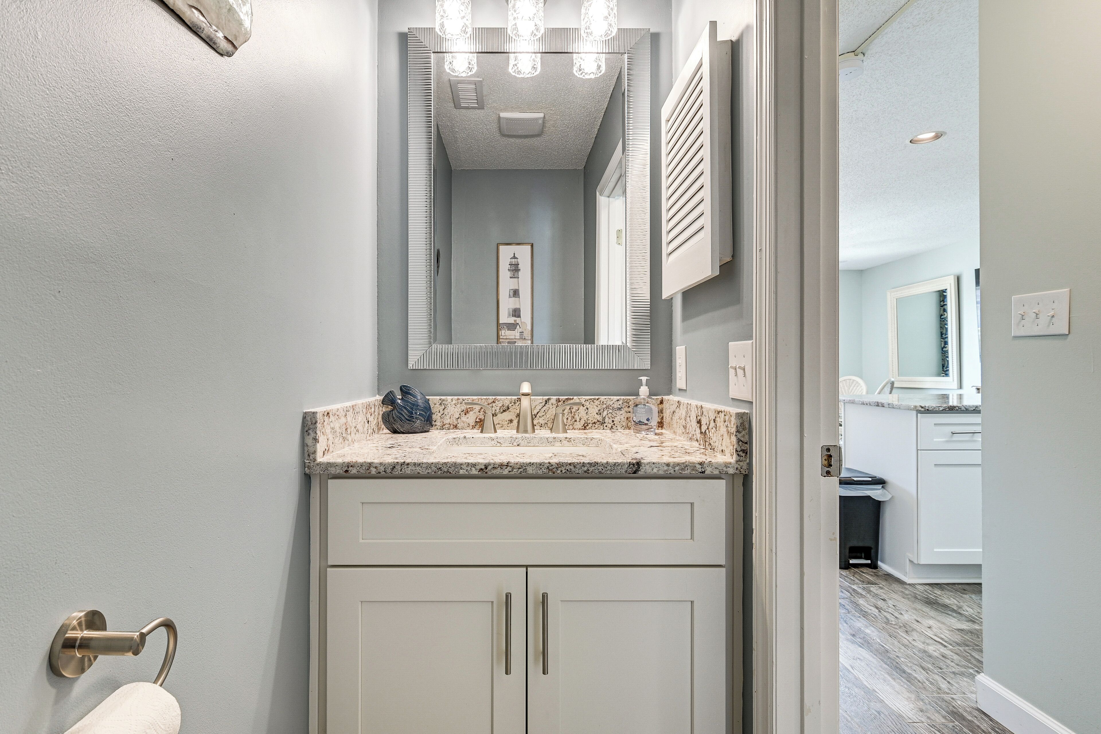 A bathroom with a marble sink, a towel rack, and a mirror above the sink.