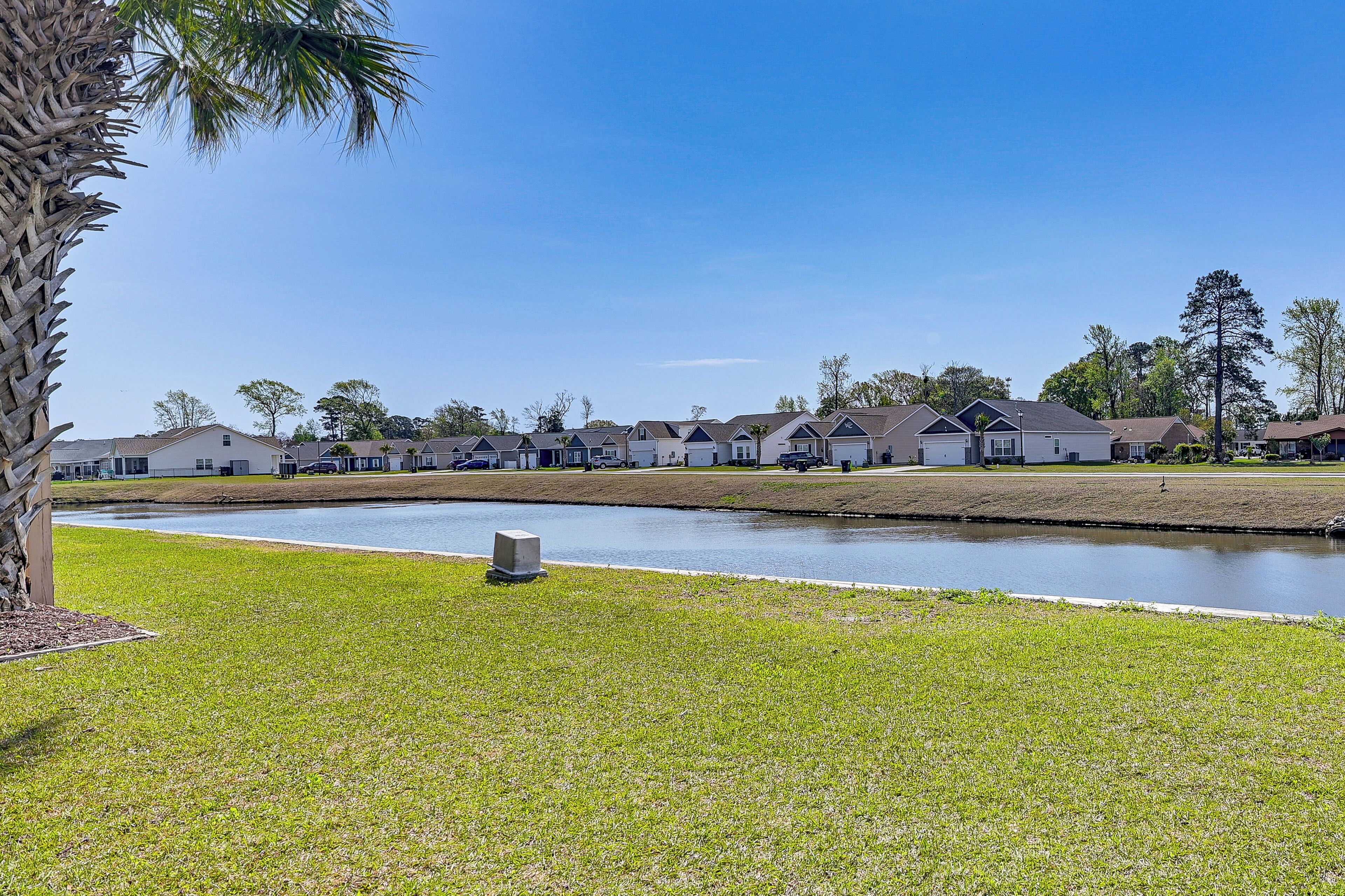 A residential area with houses, a grassy lawn, and a body of water.