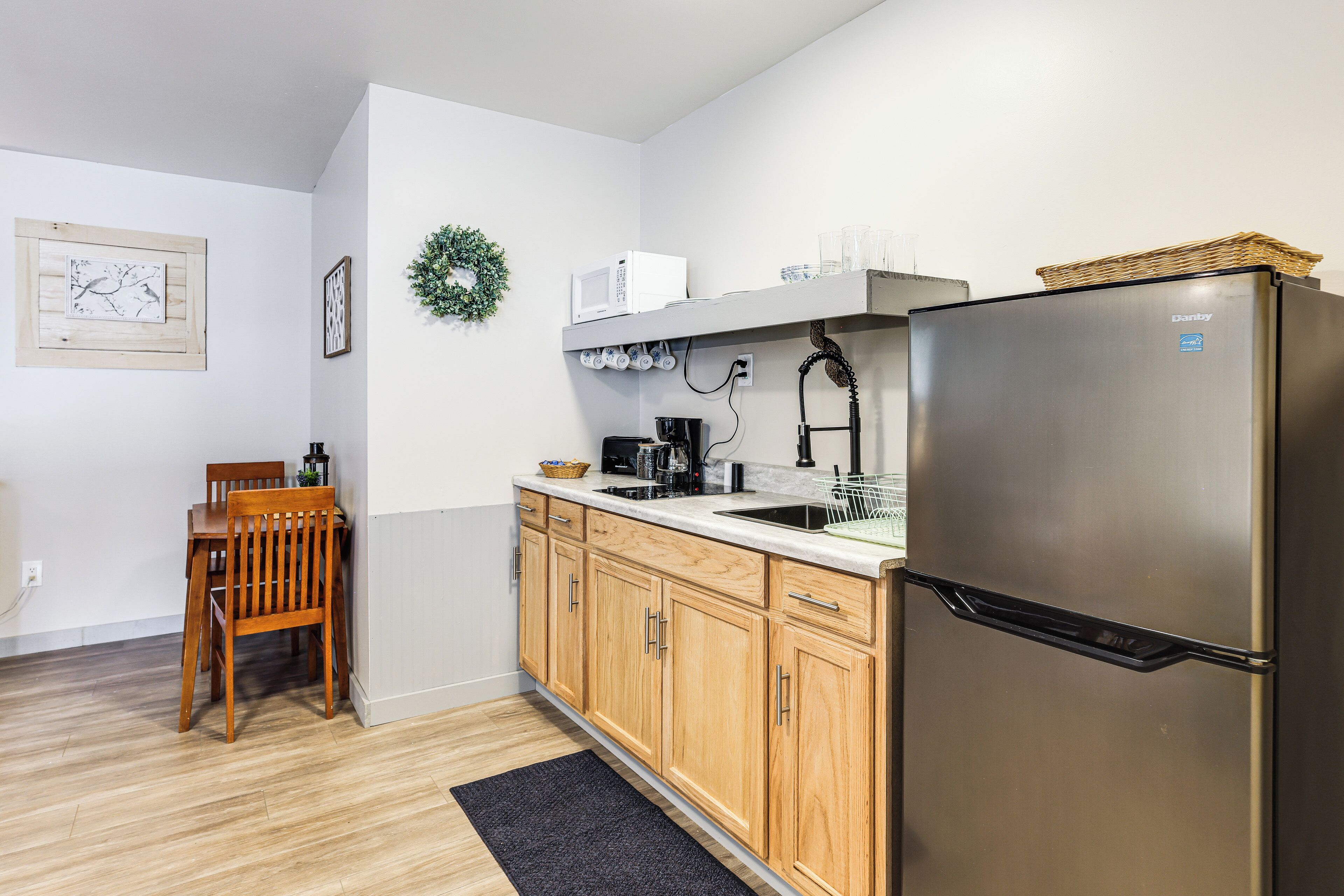 A kitchen with wooden cabinets, a stainless steel refrigerator, a microwave, and a coffee maker.