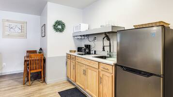 A kitchen with wooden cabinets, a stainless steel refrigerator, a microwave, and a coffee maker.