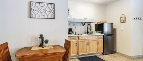 Une cuisine moderne avec des meubles en bois, un réfrigérateur en acier inoxydable et un coin repas comprenant une table et des chaises en bois.