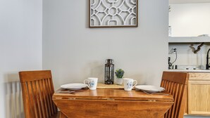 A dining table with two chairs, a decorative wall piece, and a kitchen area in the background. - < 1 Mi to Boat Launch! Schroon Lake Basecamp (Schroon Lake)