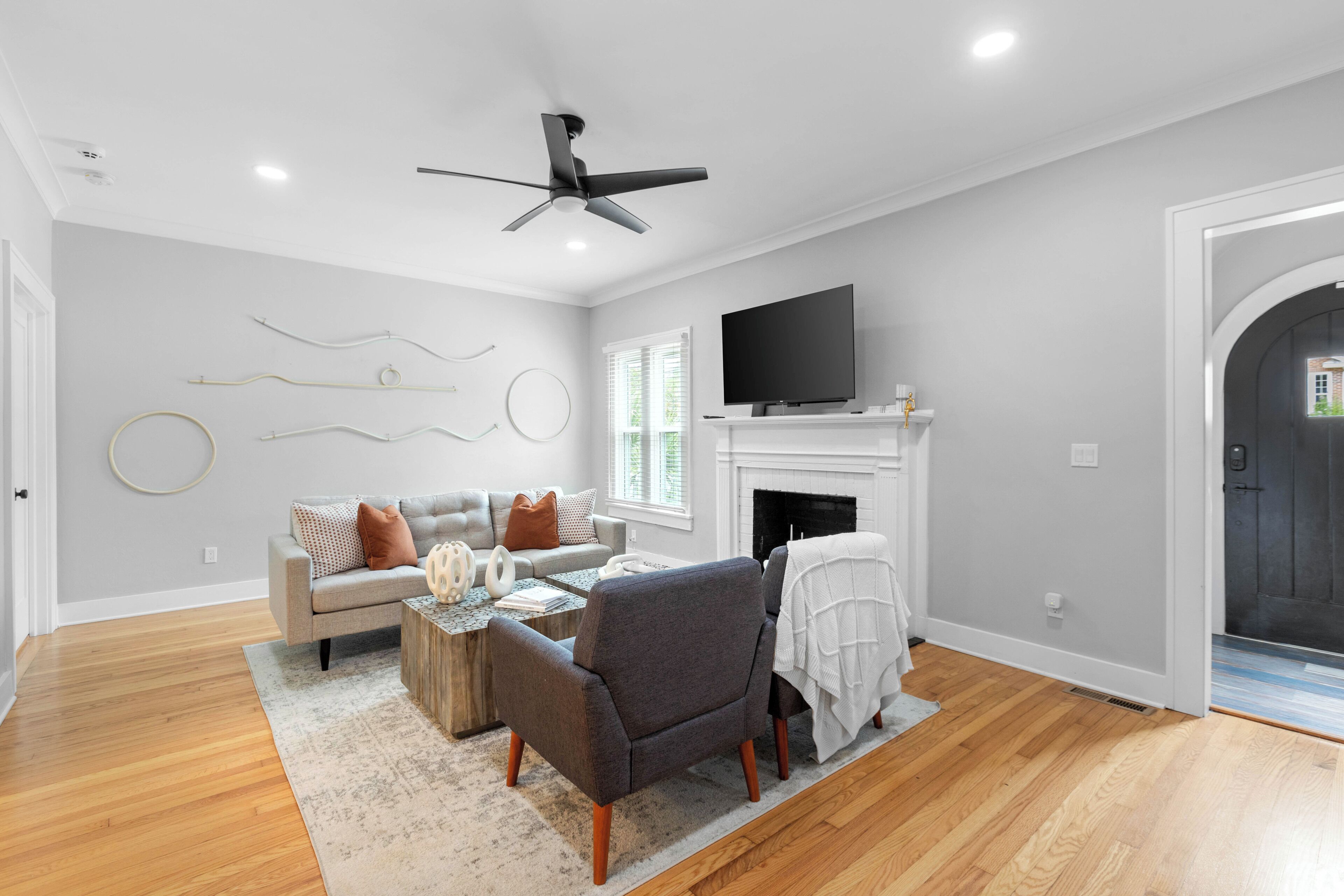 Un salon comprenant un canapé, un fauteuil, une table basse, une cheminée, un téléviseur et des œuvres d’art décoratives au mur.