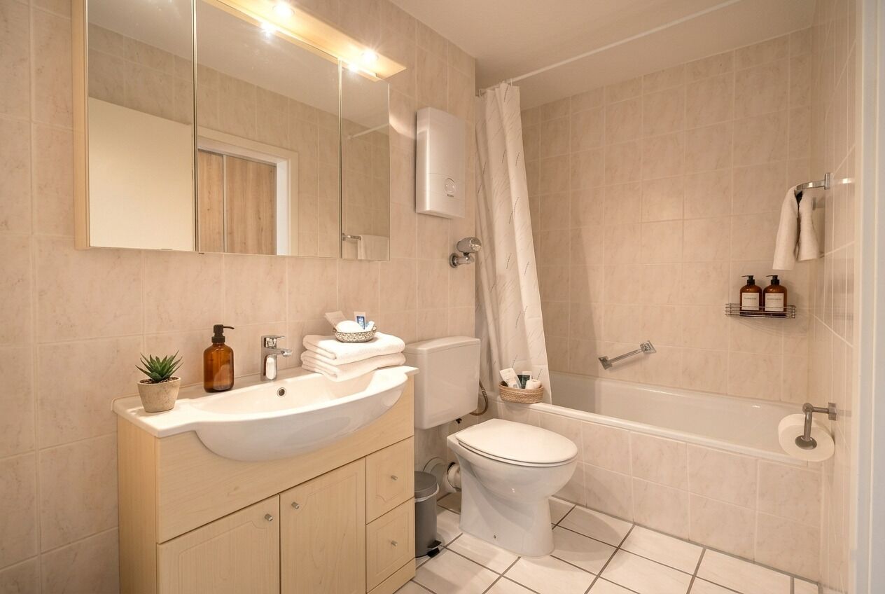 Une salle de bain moderne équipée d’un lavabo, de toilettes et d’une baignoire.