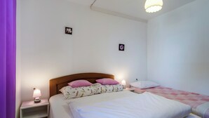 Quarto com cama, mesas de cabeceira, abajur e relógio de parede.