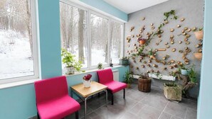 Une pièce dotée d’une grande fenêtre, d’une décoration murale en bois, d’une table, de deux chaises et de plantes en pot.