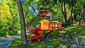 Une aire de jeux avec un toboggan, des structures d’escalade et une petite construction qui ressemble à une maison.