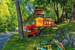 A playground with a slide, climbing structures, and a small house-like structure.