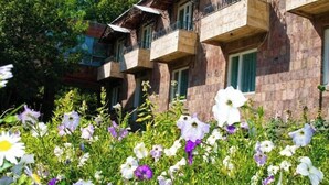 Un immeuble doté de nombreux balcons et d’un jardin où poussent différentes sortes de fleurs.