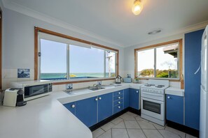 Une cuisine avec une grande fenêtre, une cuisinière et un four à micro-ondes.