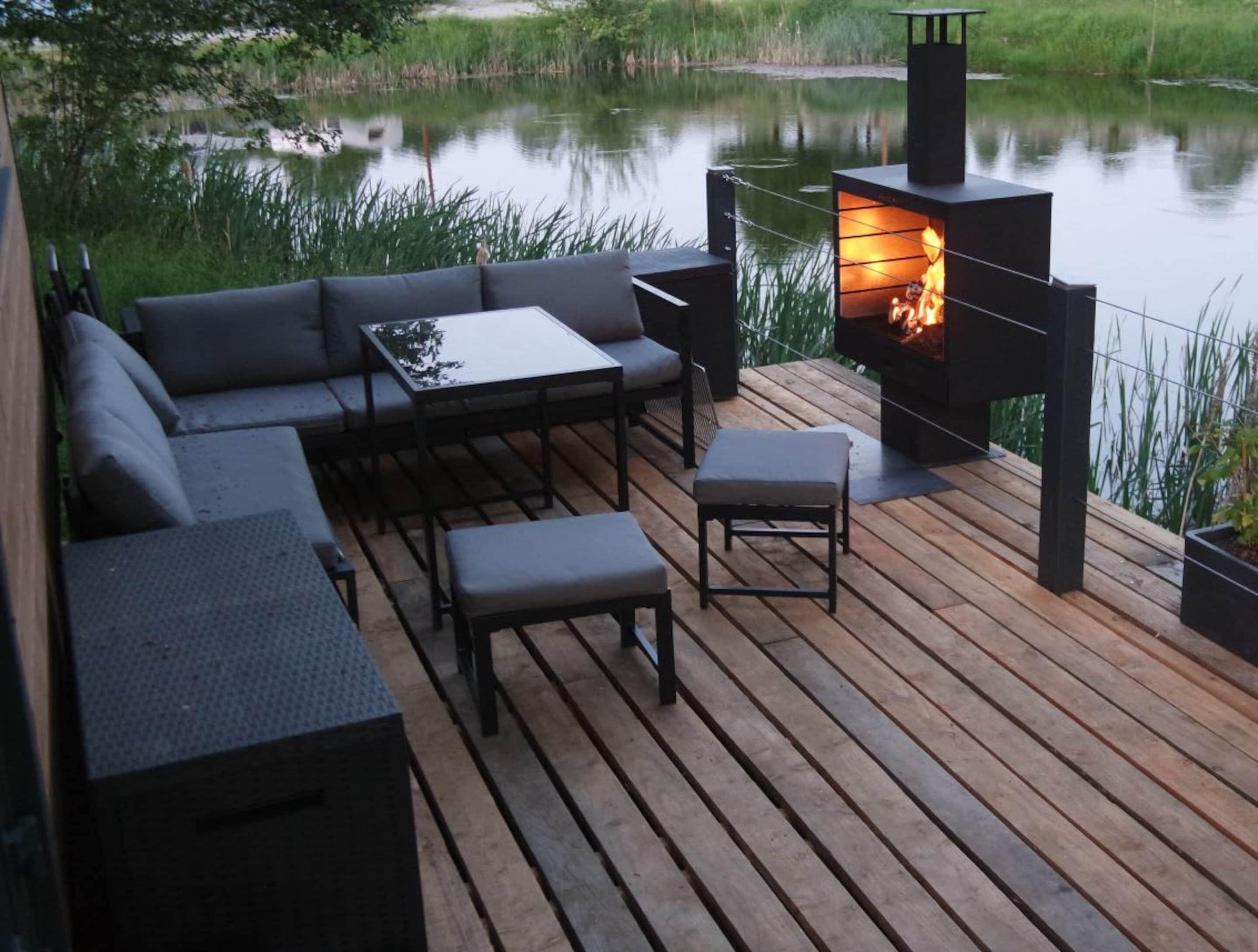Une terrasse avec un canapé, des tables et une cheminée.