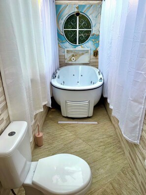 A bathroom with a bathtub, toilet, and a window with a decorative design.