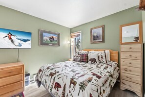 Een slaapkamer met een bed, een dressoir en een aan de muur bevestigde televisie.