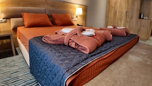 Une chambre d’hôtel avec un lit, des oreillers, une table de chevet et une lampe.
