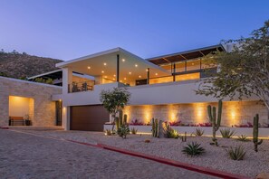 A modern multi-story house with a covered patio, a garage, and a landscaped garden with cacti. - Dual Modern Luxe Villas Sleeps 22 w/ Pools, Hot Tubs & Ocean Views Near Marina (Cabo San Lucas)