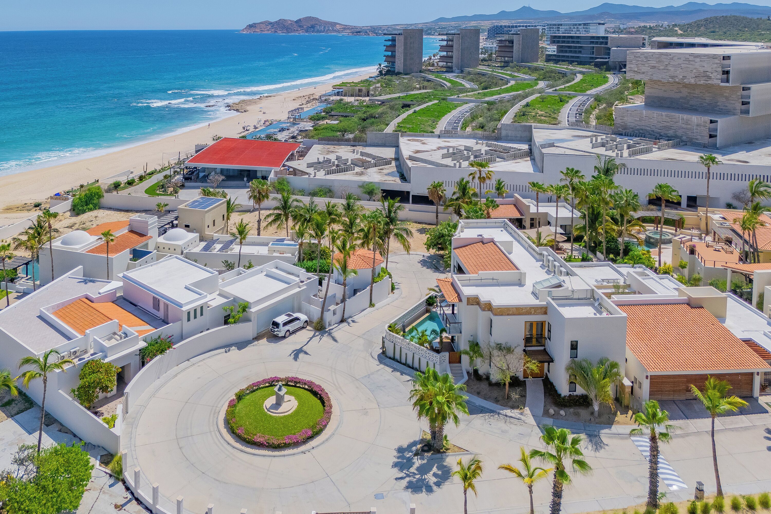 Un resort costero con arquitectura moderna, un patio central y vista al mar.