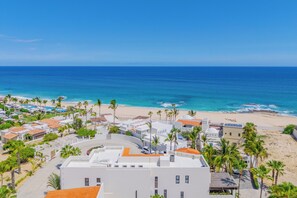 A coastal resort with white buildings, palm trees, and a beach. - Beachfront 12BR Compound w/ Pools, Hot Tubs, Game Rooms & Ocean Views Cabo (Cabo San Lucas)