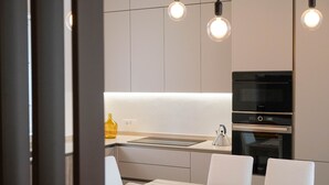 Eine moderne Küche mit Einbauofen, Mikrowelle und Spüle. Über der Arbeitsplatte befinden sich Pendelleuchten.