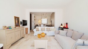 Ein modernes Wohnzimmer mit Sofa, Couchtisch, Fernseher und Essbereich.