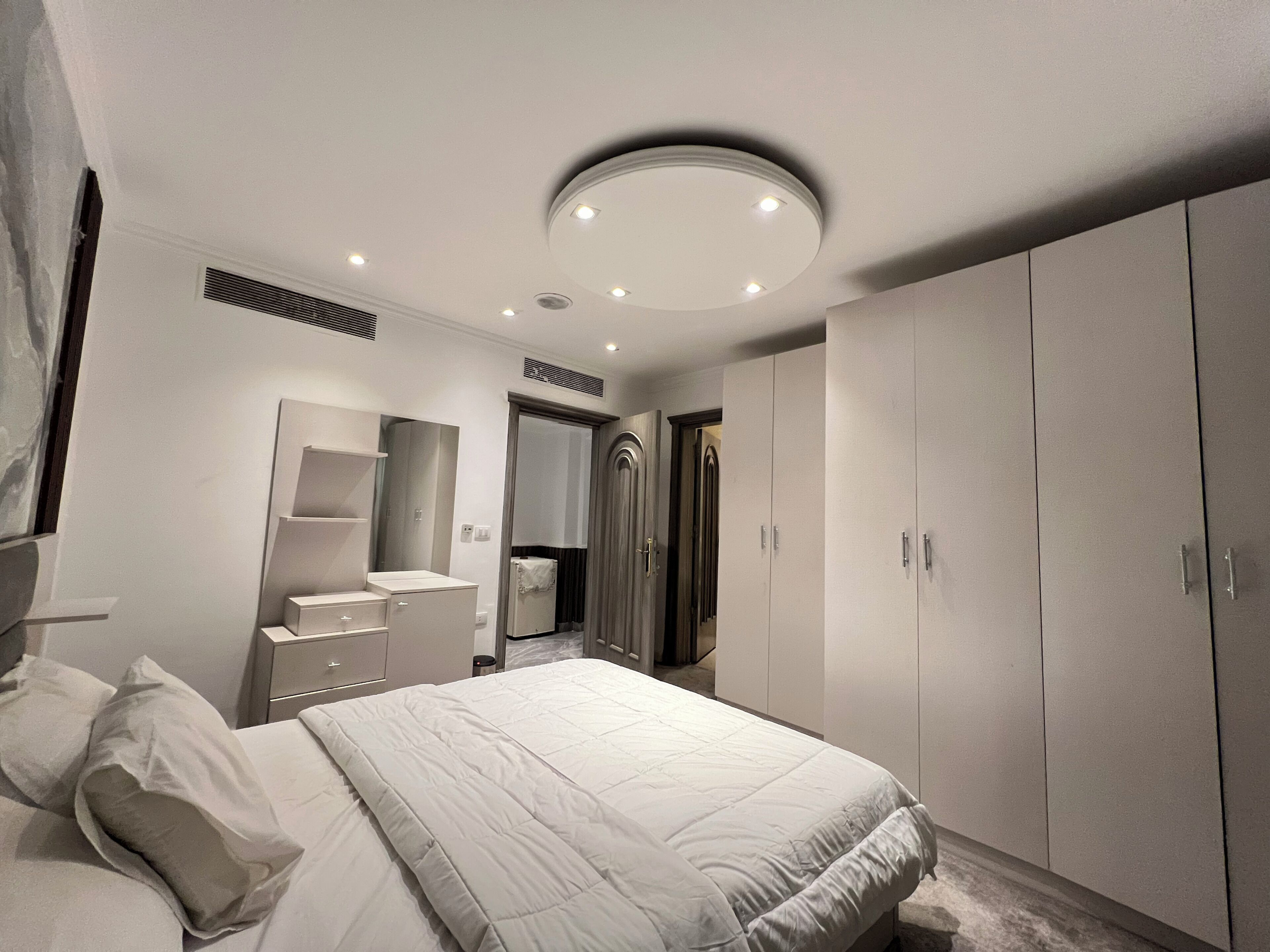 Ein Schlafzimmer mit einem Bett, einem Kleiderschrank, einem Schminktisch und einem Spiegel.