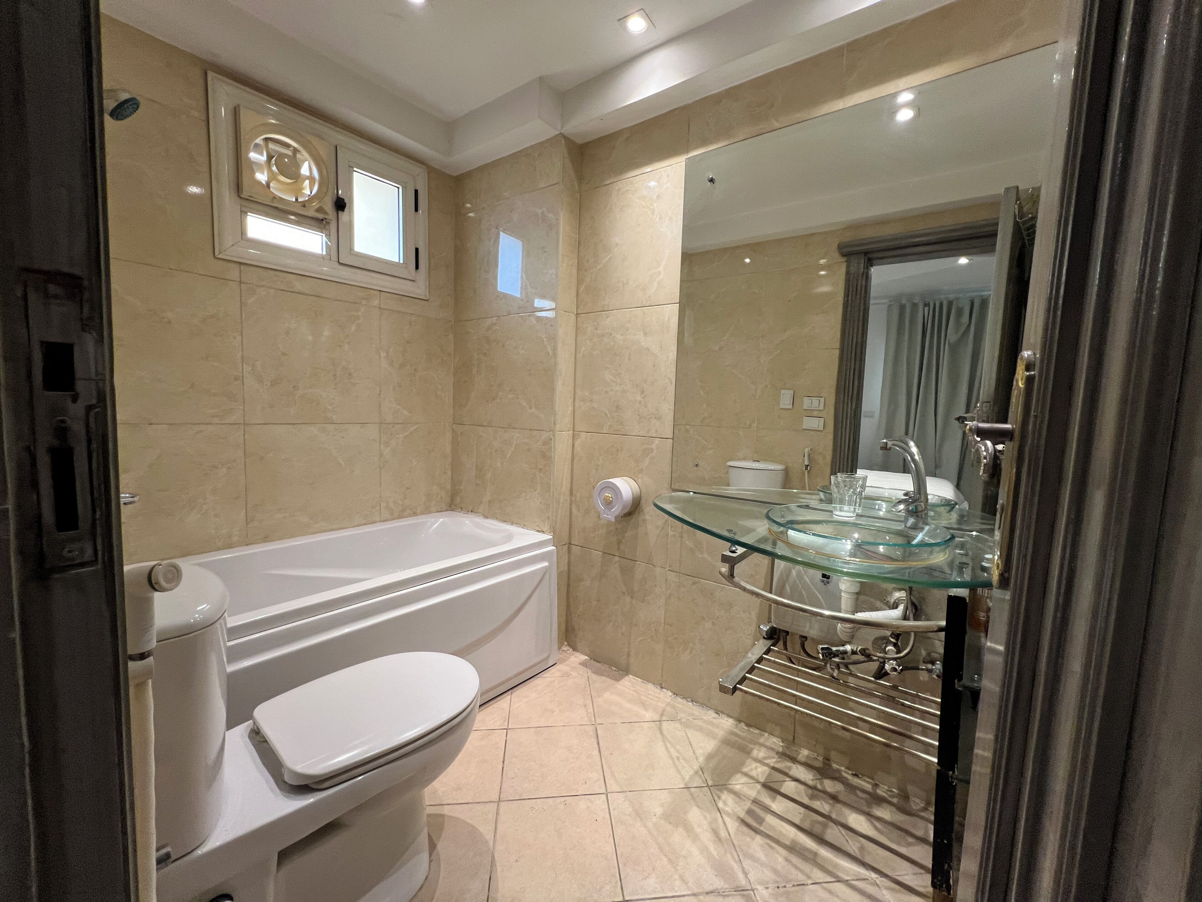 Une salle de bain moderne avec un lavabo entouré de parois en verre, une baignoire et des toilettes.