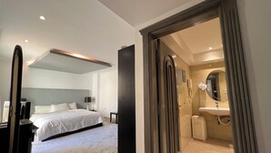 Een moderne hotelkamer met een groot bed, een aparte badkamer met spiegel en wastafel, en een inloopkast.