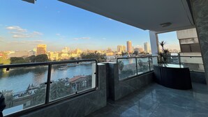 Een moderne hotelkamer met een ruim balkon, uitzicht op een stadshemelbeeld en een rivier.
