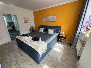 A modern bedroom with a large bed, a bedside table, a nightstand, and a view of the hallway. - Thaleblick Apartment with a rooftop terrace & mountain views   (Thale)