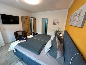 Ein Schlafzimmer mit einem Bett, einem Fernseher, einem Kleiderschrank und einem Bild an der Wand.