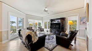 A spacious living room with a fireplace, leather sofas, a coffee table, and a television. - 2418 Windsor II - Oceanfront 4-Bed/4-Bath Villa - Fantastic Wrap Around Balcony! (Hilton Head Island)
