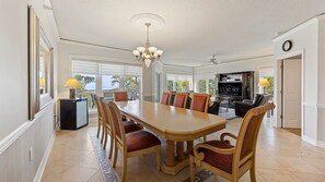 Un vaste espace dédié à la salle à manger, comprenant une grande table, des chaises et un lustre.