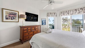 Une chambre à coucher avec un lit, une commode, un ventilateur de plafond, une fenêtre donnant sur un beau paysage et un panneau accroché au mur.