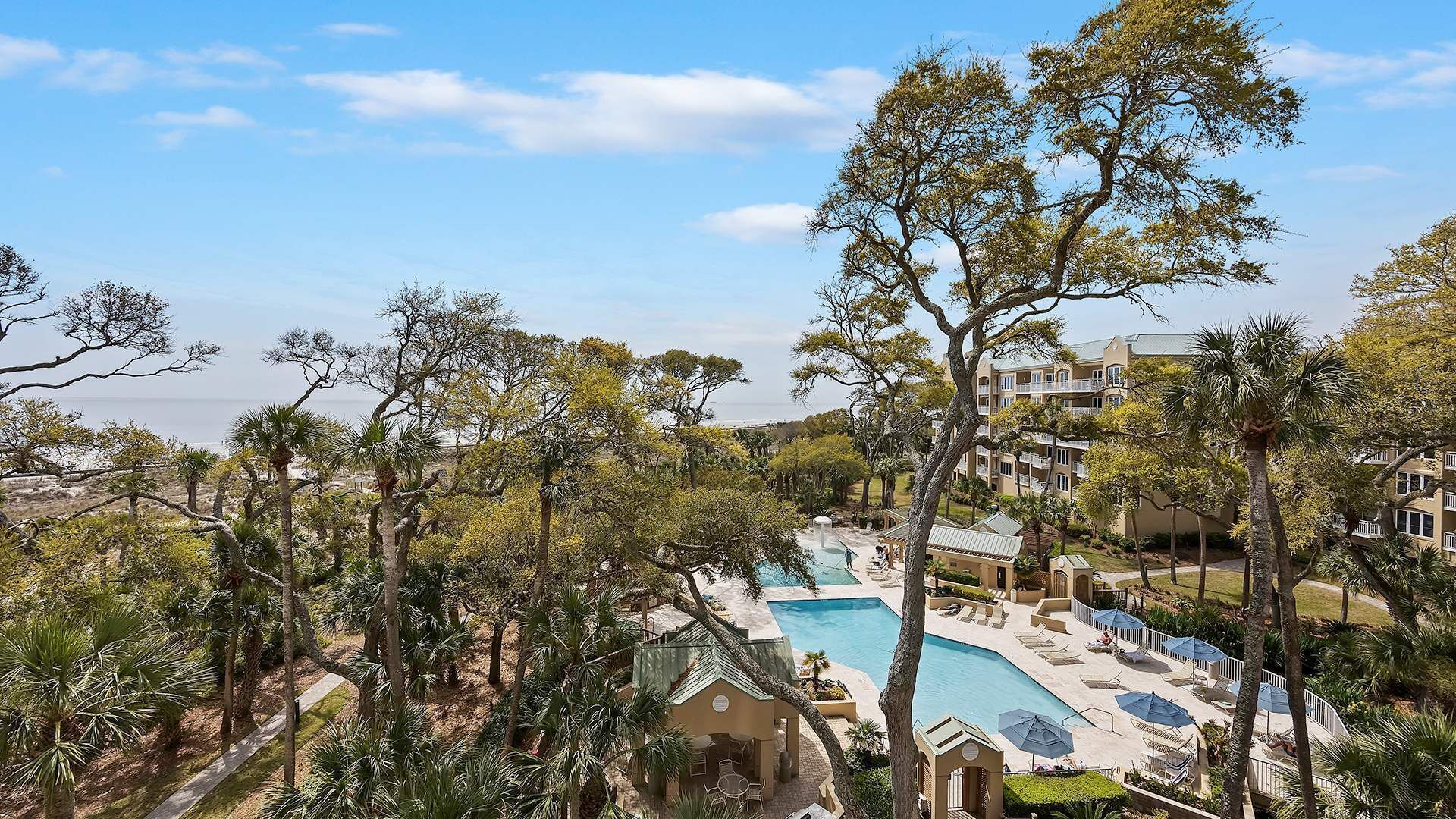 Et resort med swimmingpool, palmer og havudsigt.
